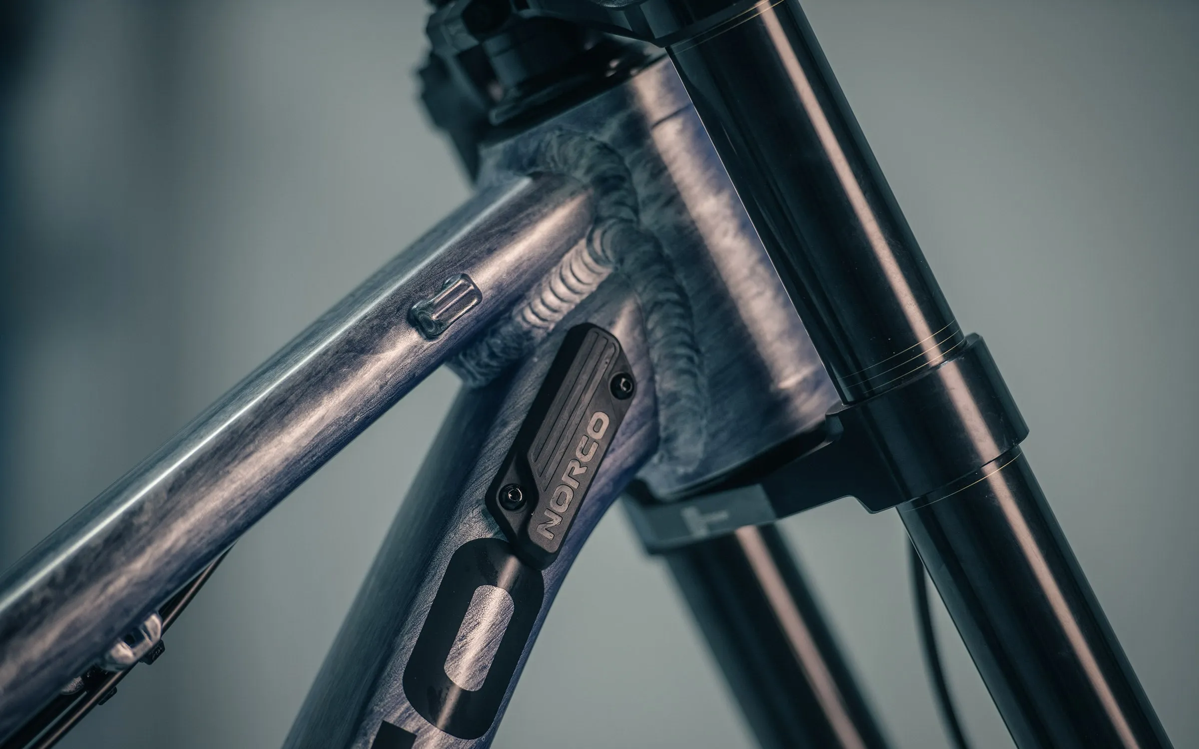 The Team DH's head tube welds and Norco cable guide, fork stanchions alongside
