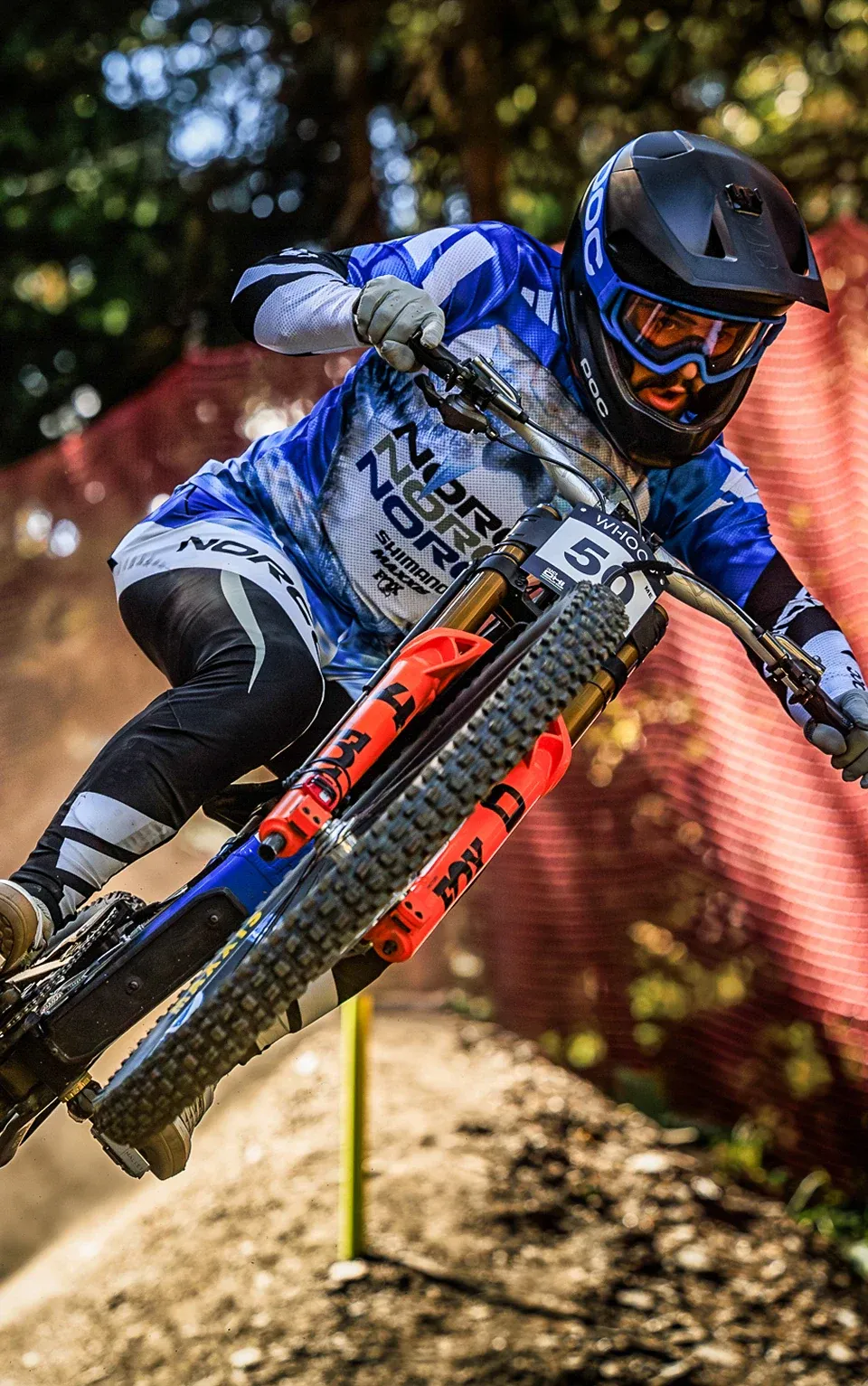 A Norco rider cornering hard on a race track, dust rising off the berm